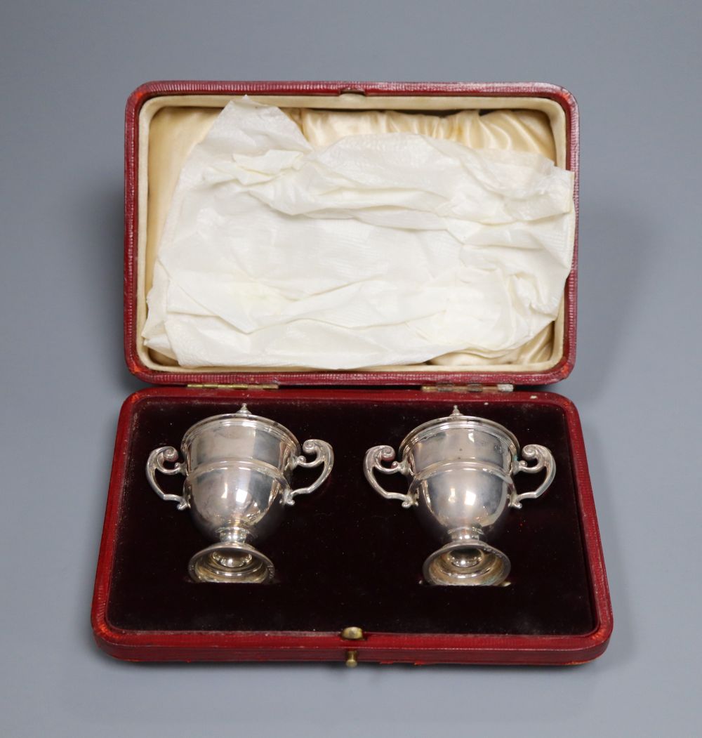 A cased pair of late Victorian small silver trophy shaped pepper pots, Horace Woodward & Co, London, 1899, 67mm,